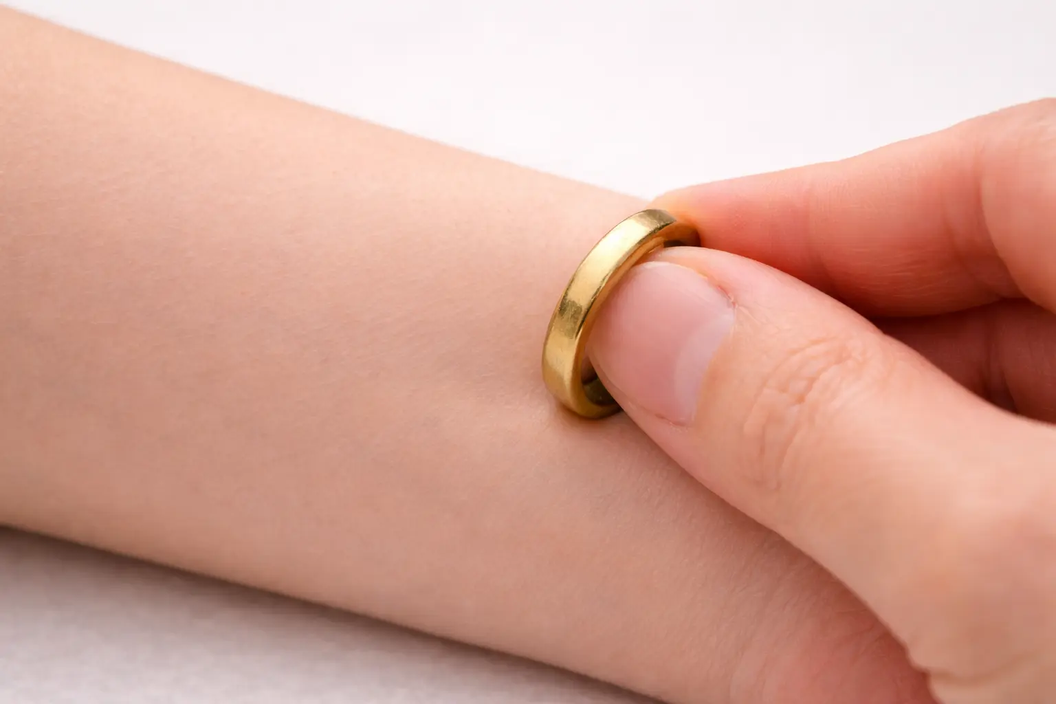 skin discoloration test for real gold showing a gold ring pressed against a forearm with no green or black marks on the skin